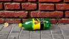 Una botella de plástico, verde y regordeta, se cuela sin glamour en el paisaje urbano de la Rosario de la distopía Milei.