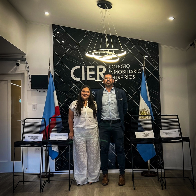 Villegas y Tropini, de la lista oficialista Futuro Inmobiliario, junto a los asientos vacíos que dejó la oposición durante el debate de candidatos.
