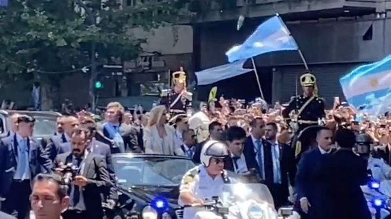 Captura del momento en el que la botella vuela sobre la dupla Milei.