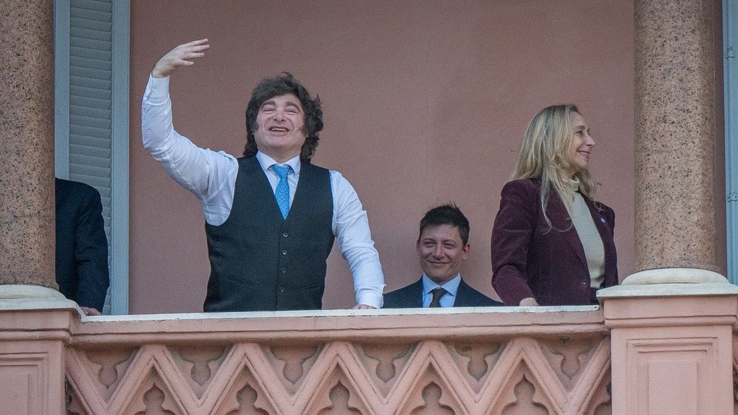 El Presidente Javier Milei, al borde del balcón de la Casa Rosada. A sus espaldas, Karina Milei y Santiago Caputo.