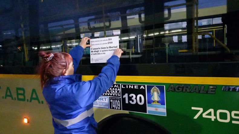 Empleada de la CNRT coloca carteles con información tarifaria en colectivos y trenes